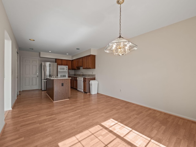 kitchen featuring a chandelier, white appliances, light wood-style floors, and decorative light fixtures