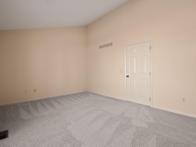 empty room featuring visible vents, carpet, and lofted ceiling