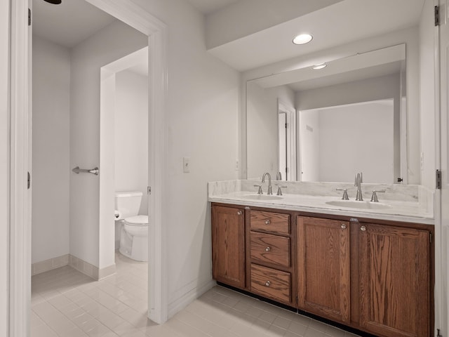 bathroom featuring double vanity, toilet, tile patterned floors, and a sink