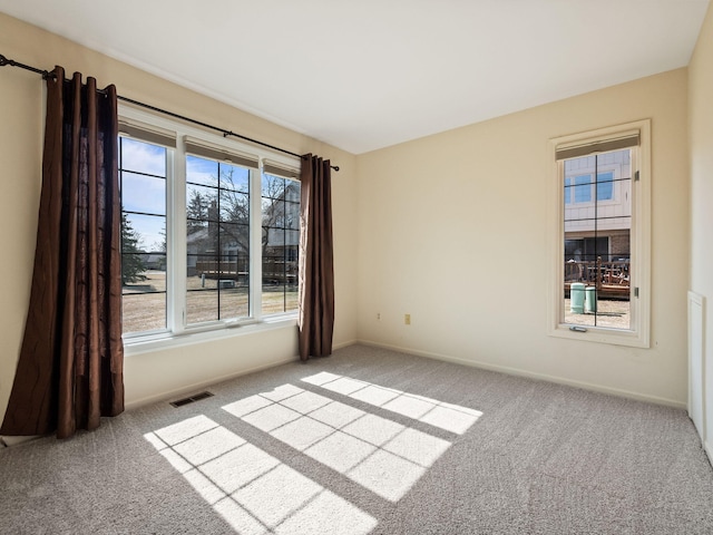 empty room with carpet flooring, baseboards, and visible vents