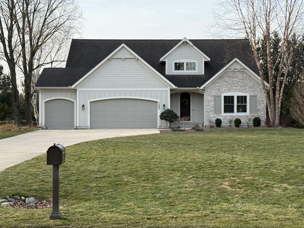 craftsman inspired home with board and batten siding, a front lawn, roof with shingles, a garage, and driveway