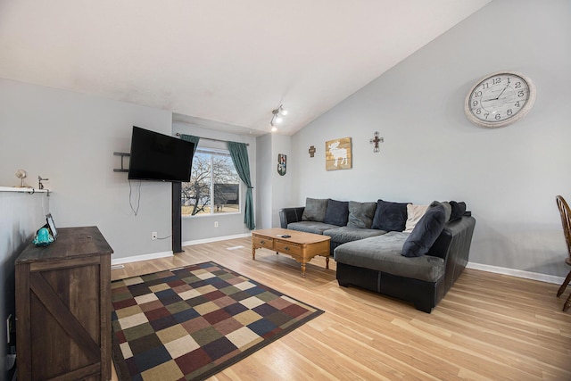 living area with light wood-type flooring, baseboards, and vaulted ceiling