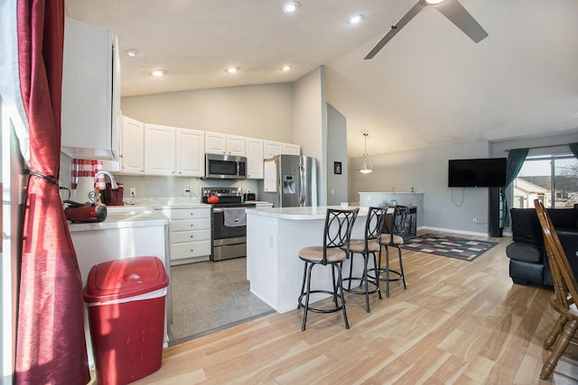 kitchen featuring a kitchen bar, a sink, white cabinetry, stainless steel appliances, and light countertops