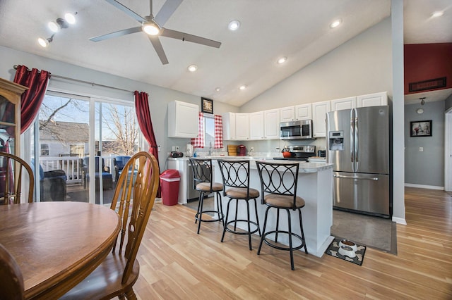 kitchen with a breakfast bar, a kitchen island, appliances with stainless steel finishes, white cabinets, and ceiling fan