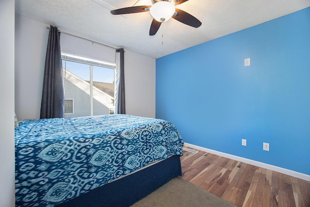 bedroom with ceiling fan, baseboards, a textured ceiling, and wood finished floors