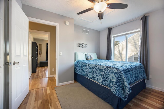 bedroom featuring visible vents, baseboards, a textured ceiling, and wood finished floors