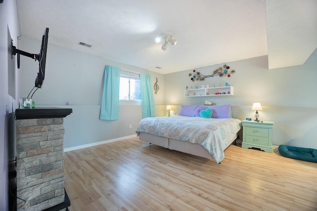 bedroom featuring visible vents, baseboards, and wood finished floors