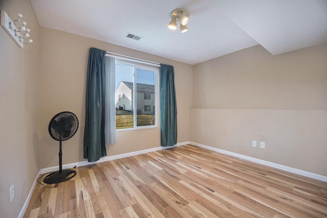 empty room with light wood-type flooring, visible vents, and baseboards