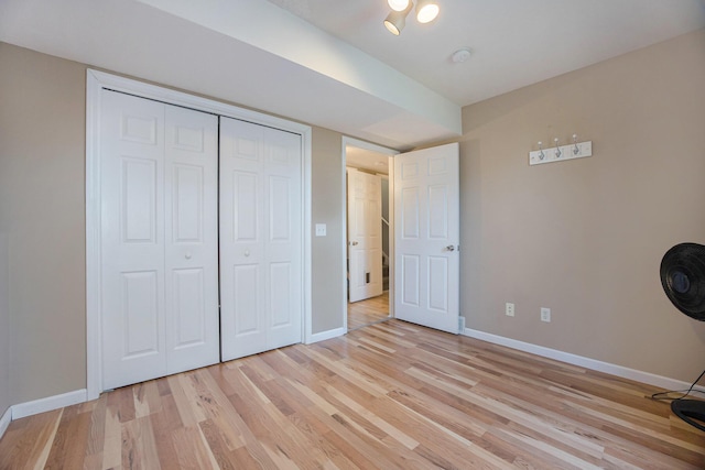 unfurnished bedroom featuring light wood finished floors, a closet, and baseboards