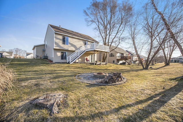 rear view of house with central AC, stairs, a fire pit, a deck, and a lawn