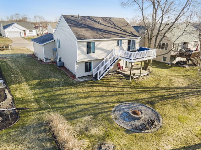 rear view of house featuring a lawn, cooling unit, stairway, roof with shingles, and a wooden deck