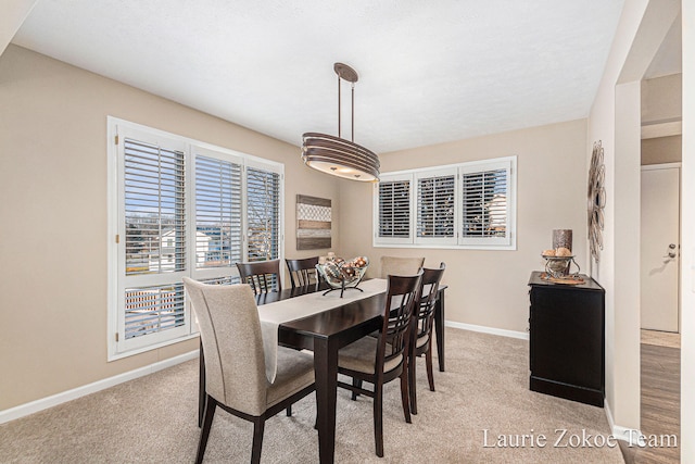 dining space featuring light colored carpet and baseboards