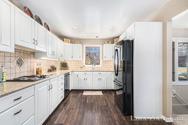 kitchen with light stone counters, black appliances, white cabinets, and dark wood-style flooring