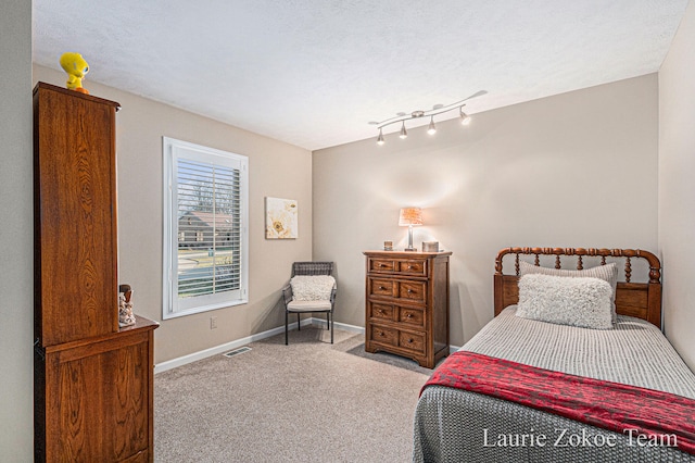 bedroom with visible vents, a textured ceiling, baseboards, and carpet