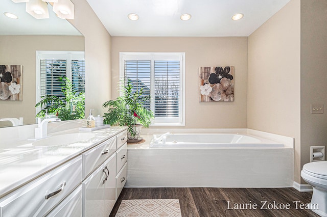 full bathroom with toilet, a garden tub, recessed lighting, wood finished floors, and vanity