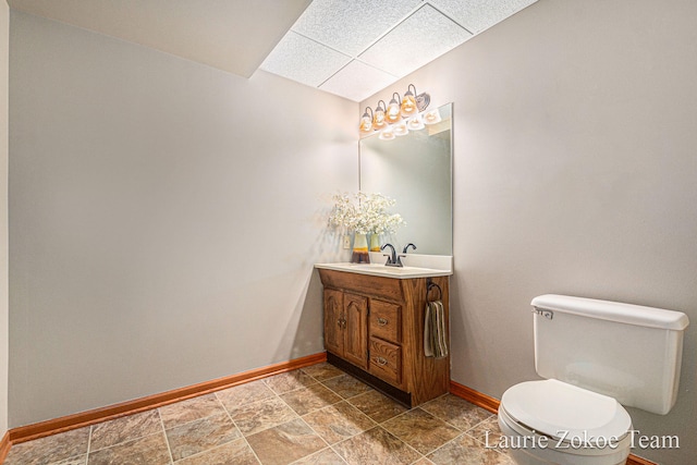 bathroom with vanity, toilet, baseboards, and stone finish flooring