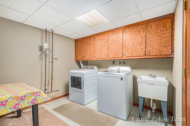 washroom with washing machine and dryer, cabinet space, baseboards, and a sink