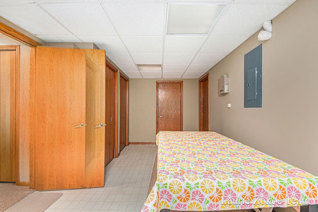 bedroom with electric panel, baseboards, and a paneled ceiling