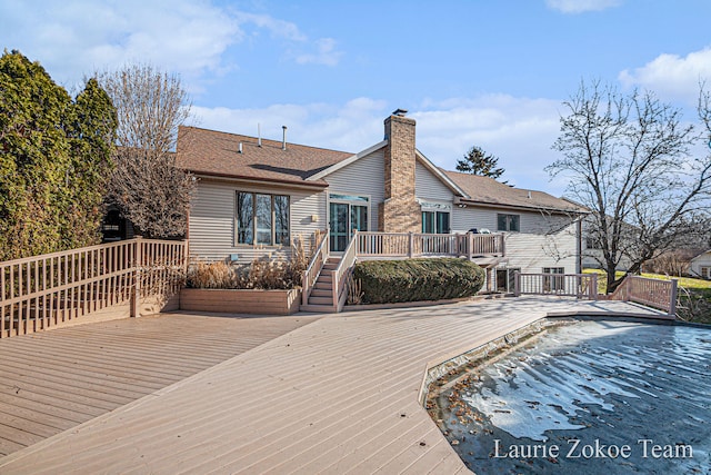 rear view of property featuring a chimney and a deck