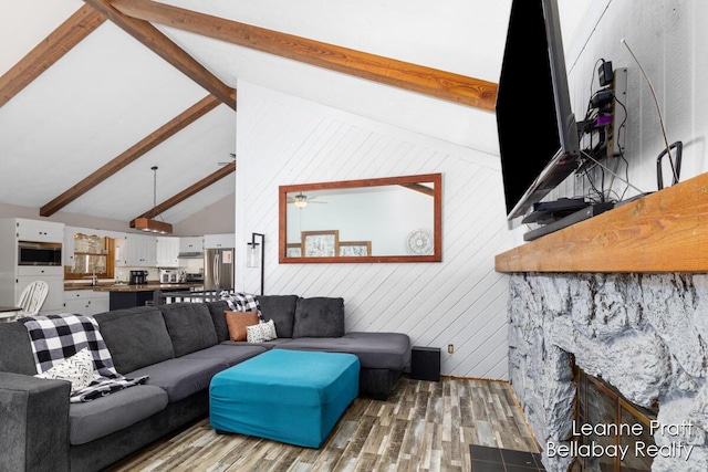 living room featuring lofted ceiling with beams, a ceiling fan, and wood finished floors