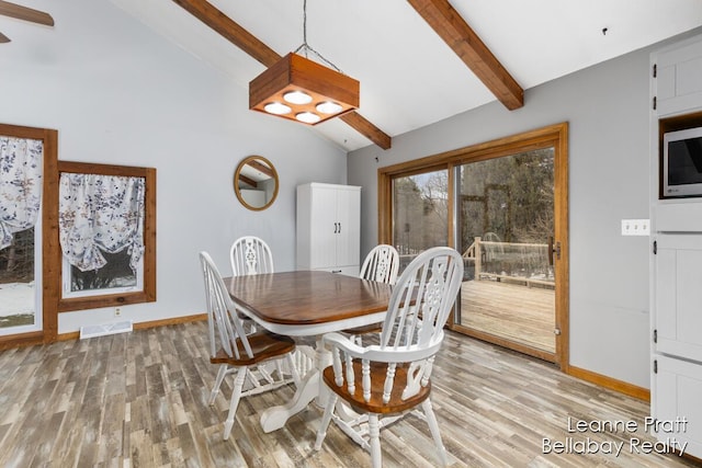 dining room featuring lofted ceiling with beams, baseboards, visible vents, and light wood-type flooring