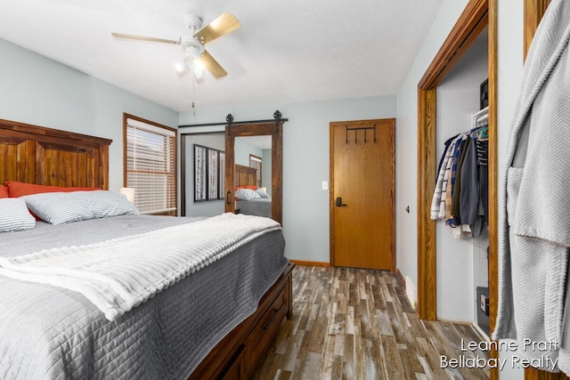 bedroom featuring baseboards, a barn door, wood finished floors, a closet, and a ceiling fan