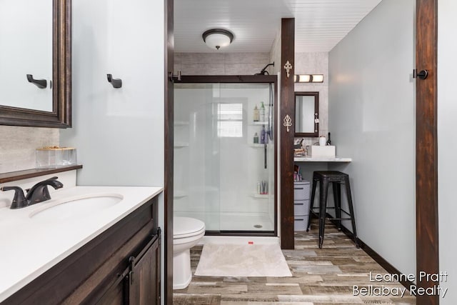 full bath featuring a shower stall, toilet, vanity, and wood finished floors