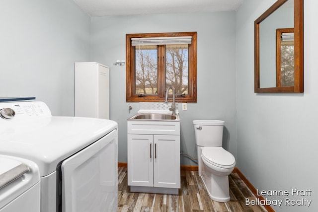 laundry room featuring laundry area, wood finished floors, separate washer and dryer, and a sink