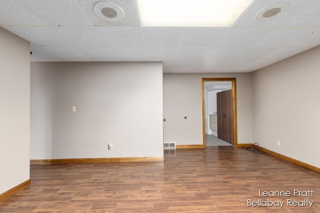 unfurnished room with a paneled ceiling, baseboards, and wood finished floors