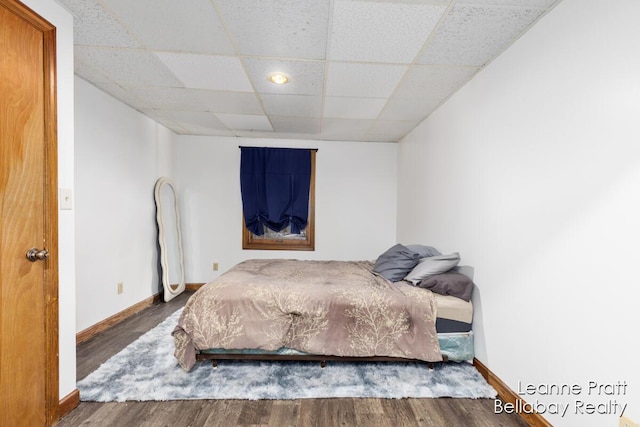 bedroom with wood finished floors, baseboards, and a drop ceiling