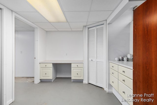 home office featuring a drop ceiling and finished concrete flooring