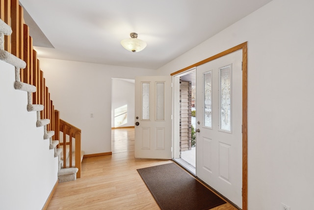 entryway featuring stairway, light wood-style flooring, baseboards, and a wealth of natural light