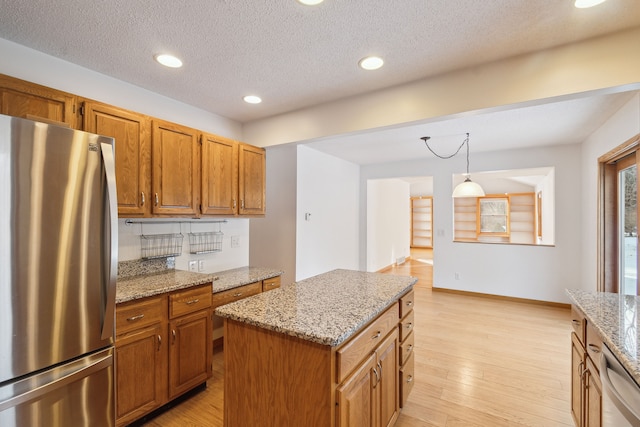 kitchen featuring light stone countertops, dishwashing machine, light wood-style flooring, brown cabinets, and freestanding refrigerator