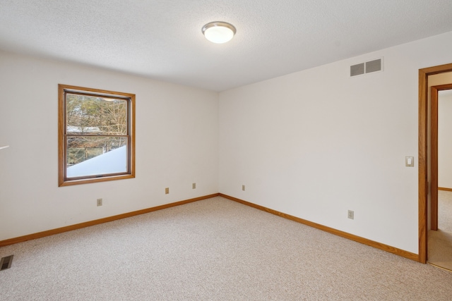 spare room with light carpet, visible vents, and a textured ceiling