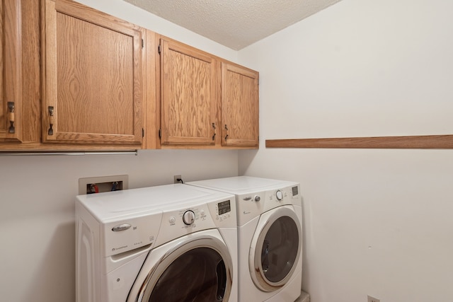 clothes washing area with cabinet space, independent washer and dryer, and a textured ceiling