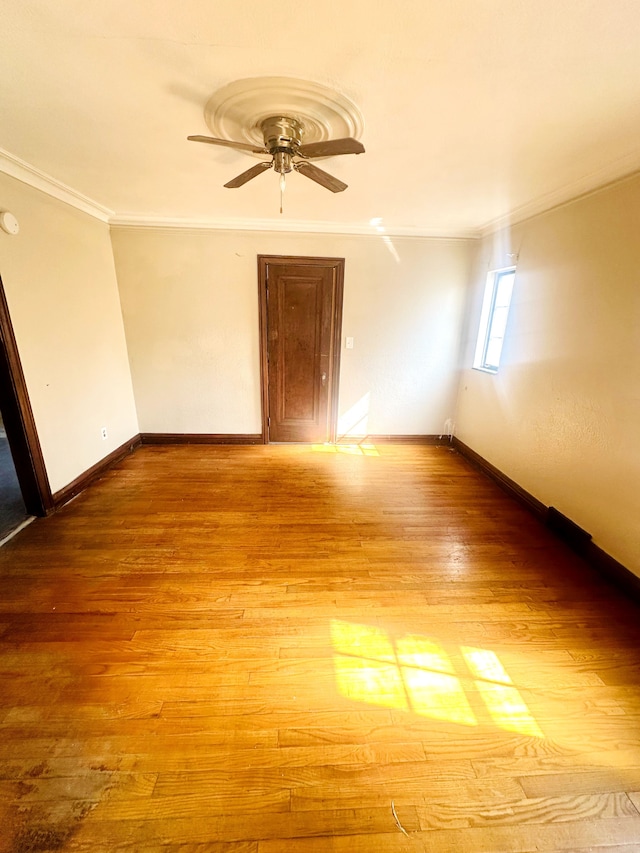 empty room featuring baseboards, wood finished floors, ceiling fan, and ornamental molding