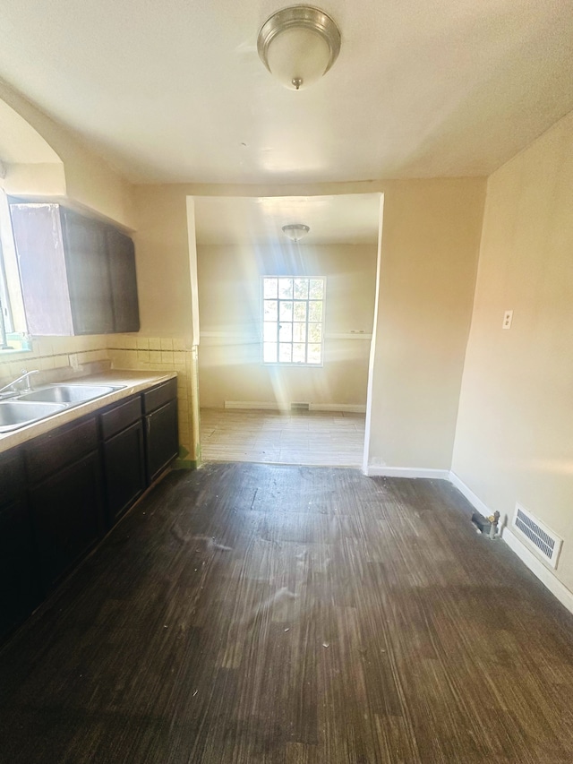 interior space with a sink, visible vents, baseboards, and wood finished floors