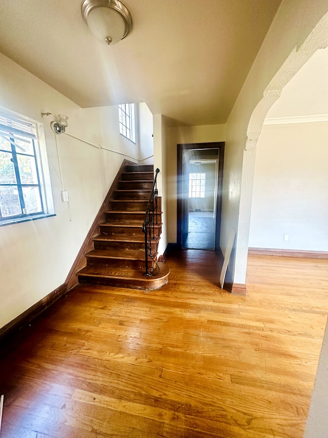 stairs featuring baseboards, arched walkways, and hardwood / wood-style flooring