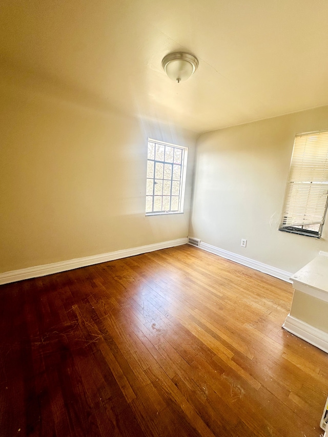 unfurnished room featuring visible vents, baseboards, and wood-type flooring