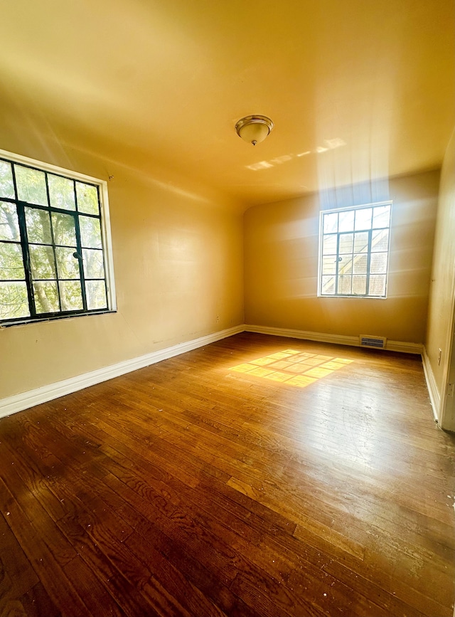 spare room featuring hardwood / wood-style floors, visible vents, and baseboards