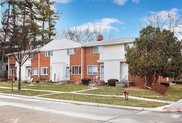 view of property featuring a front lawn, brick siding, and a chimney