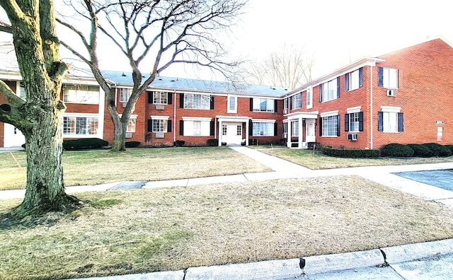 townhome / multi-family property featuring a front lawn and brick siding