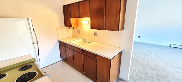 kitchen featuring freestanding refrigerator, a sink, light countertops, range with electric stovetop, and light colored carpet