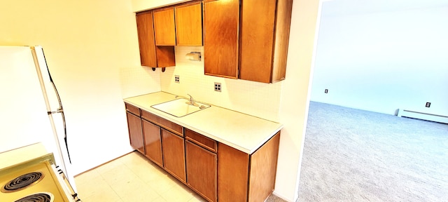 kitchen with a sink, freestanding refrigerator, light countertops, a baseboard radiator, and light colored carpet