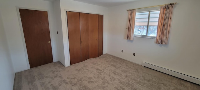 unfurnished bedroom with a closet, baseboard heating, and carpet flooring