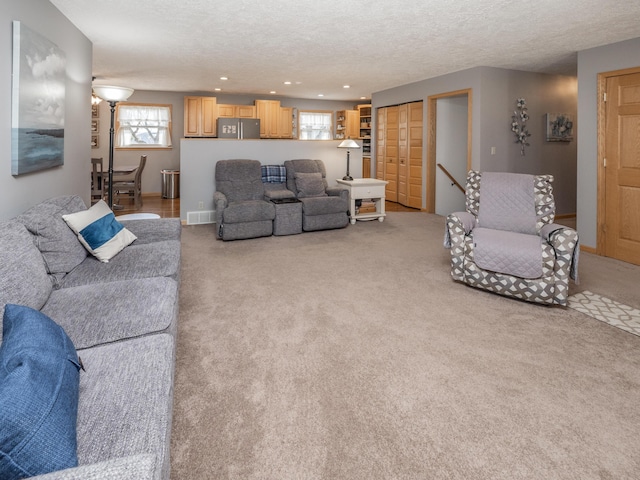 living room with visible vents, recessed lighting, a textured ceiling, and carpet