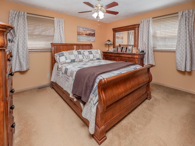 bedroom featuring baseboards, light carpet, a textured ceiling, and a ceiling fan