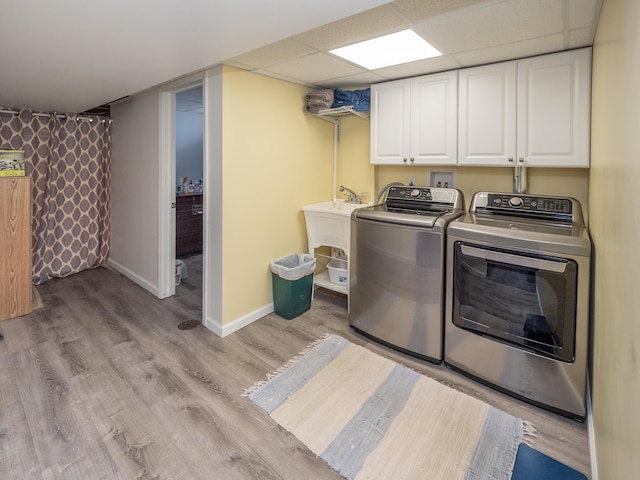 clothes washing area with cabinet space, separate washer and dryer, baseboards, and light wood finished floors