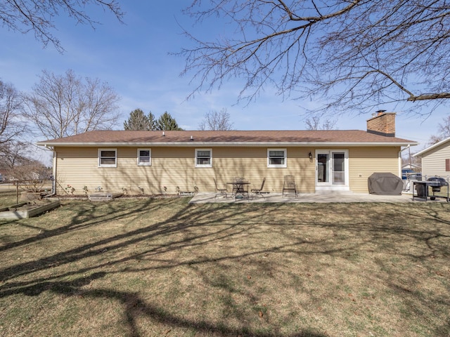 rear view of property with a patio, a lawn, and a chimney