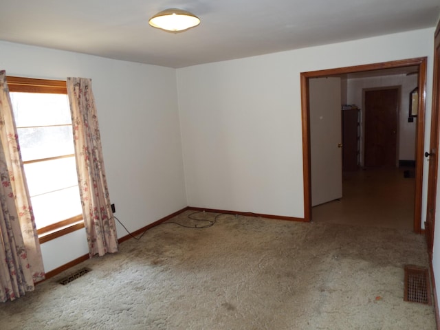 unfurnished room featuring visible vents, carpet floors, and baseboards